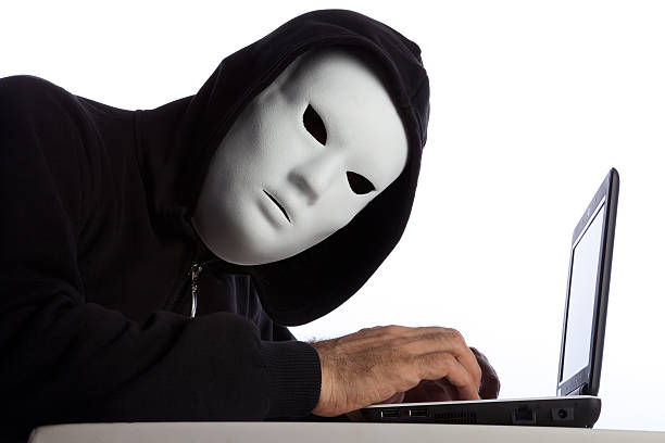 Hacker Man Wearing Mask And Hood Using Computer, Isolated On White Background